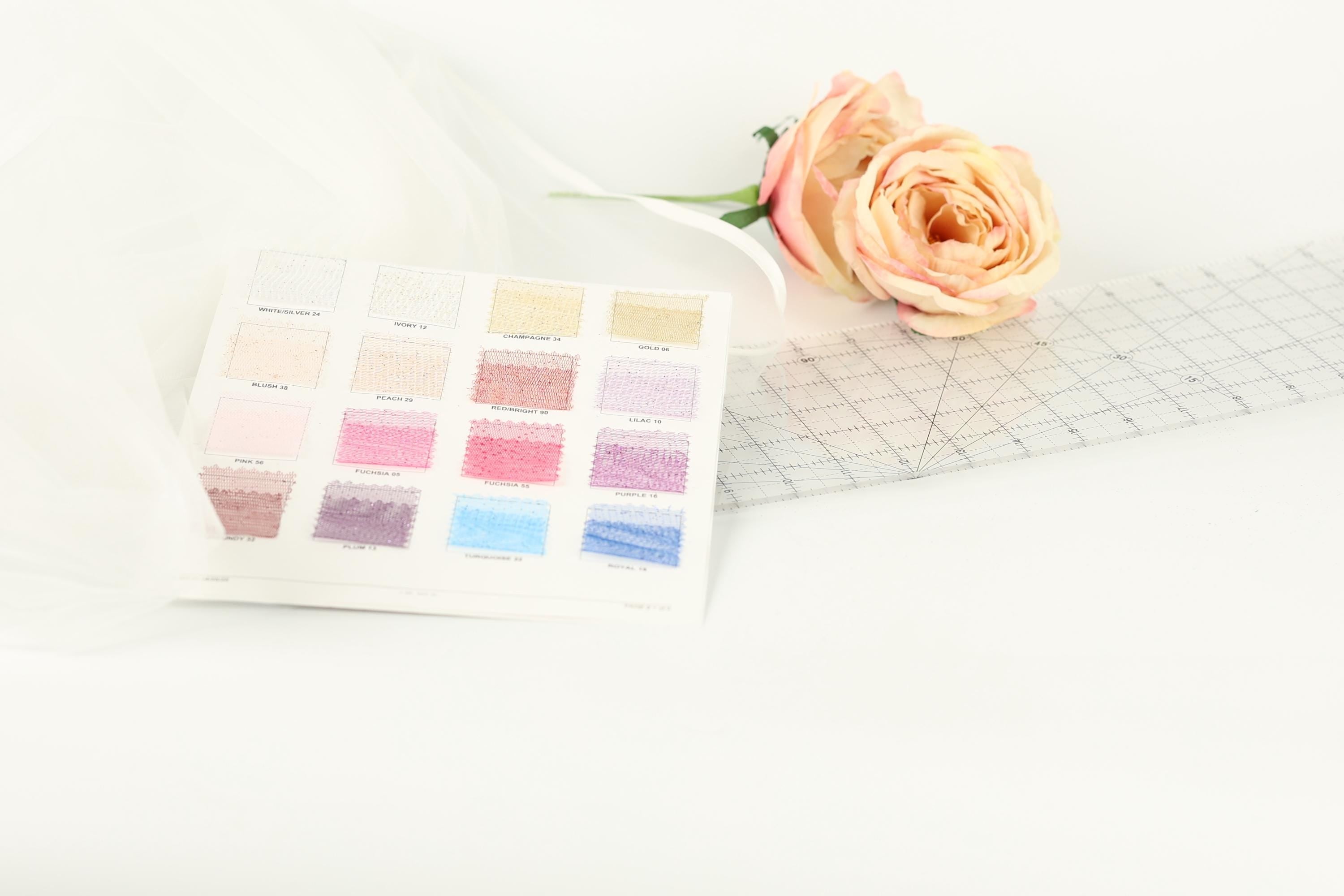 a color swatch with various shades of pink and white, along with a single pink rose and a ruler on a white background.