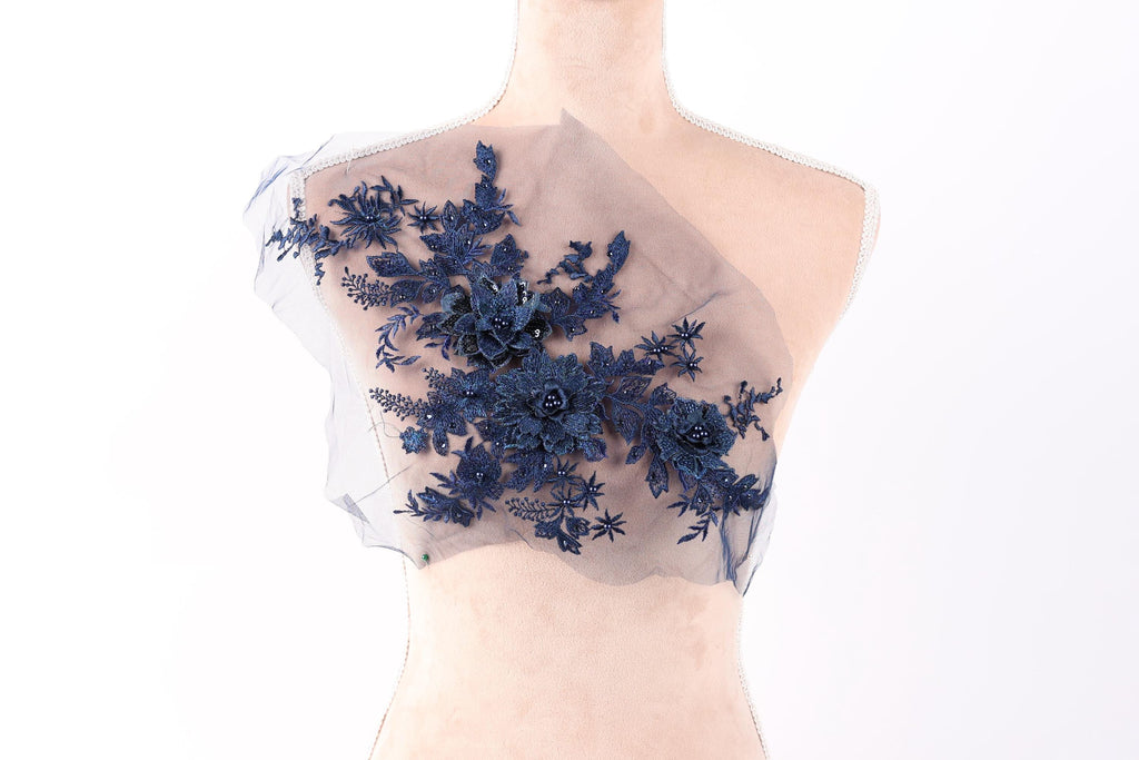 A mannequin torso with a decorative blue floral embroidered on the left side of the chest area.