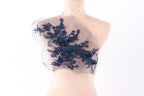 A mannequin torso with a decorative blue floral embroidered on the left side of the chest area.