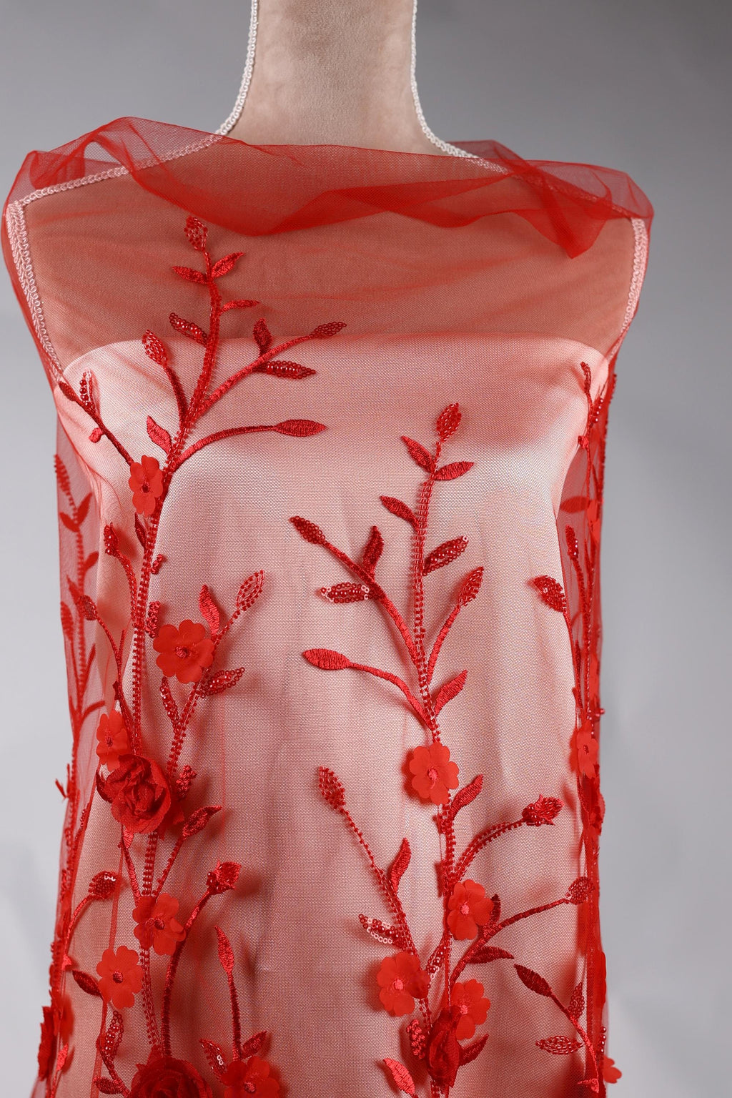 A red dress with a floral pattern on the front, featuring red flowers and leaves.