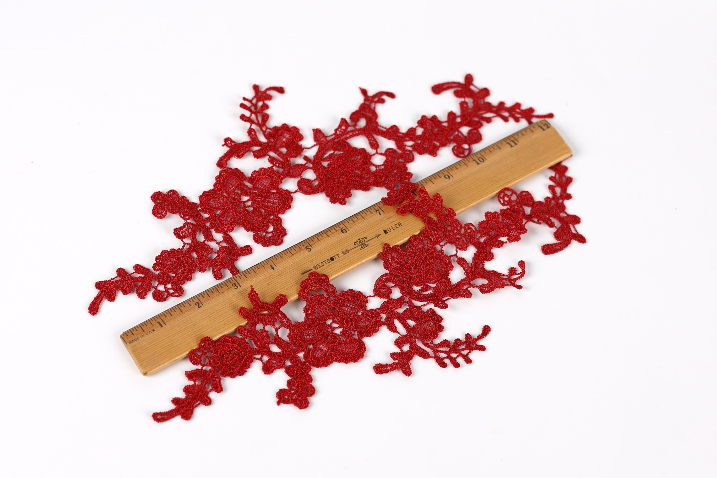 a wooden ruler placed on a white background, with red lace or fabric pieces scattered around it.