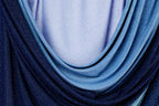 a close-up view of a fabric with blue and purple hues, featuring a textured and shiny appearance.