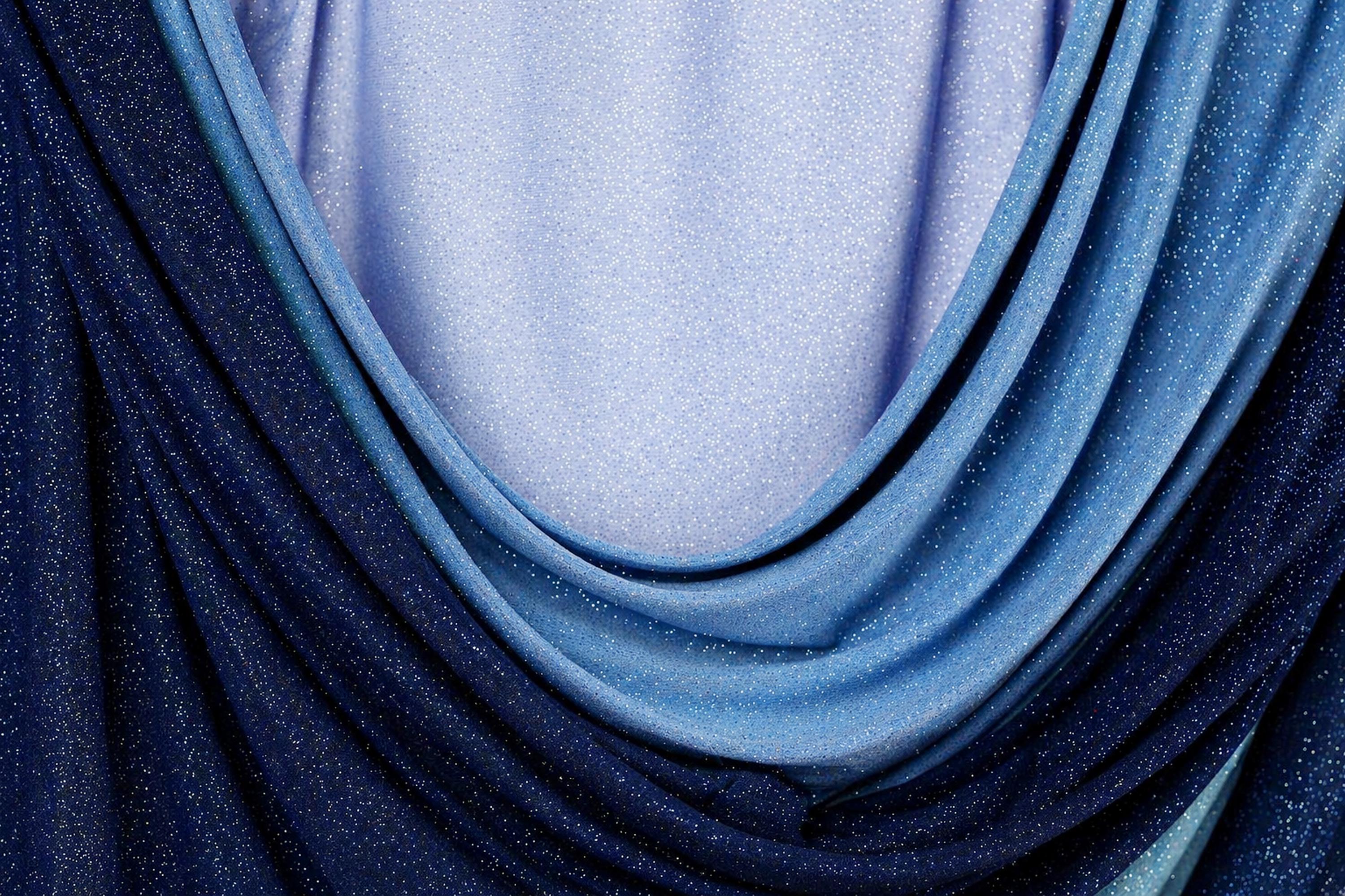 a close-up view of a fabric with blue and purple hues, featuring a textured and shiny appearance.