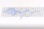 a clear ruler with blue flower-like designs placed on it.