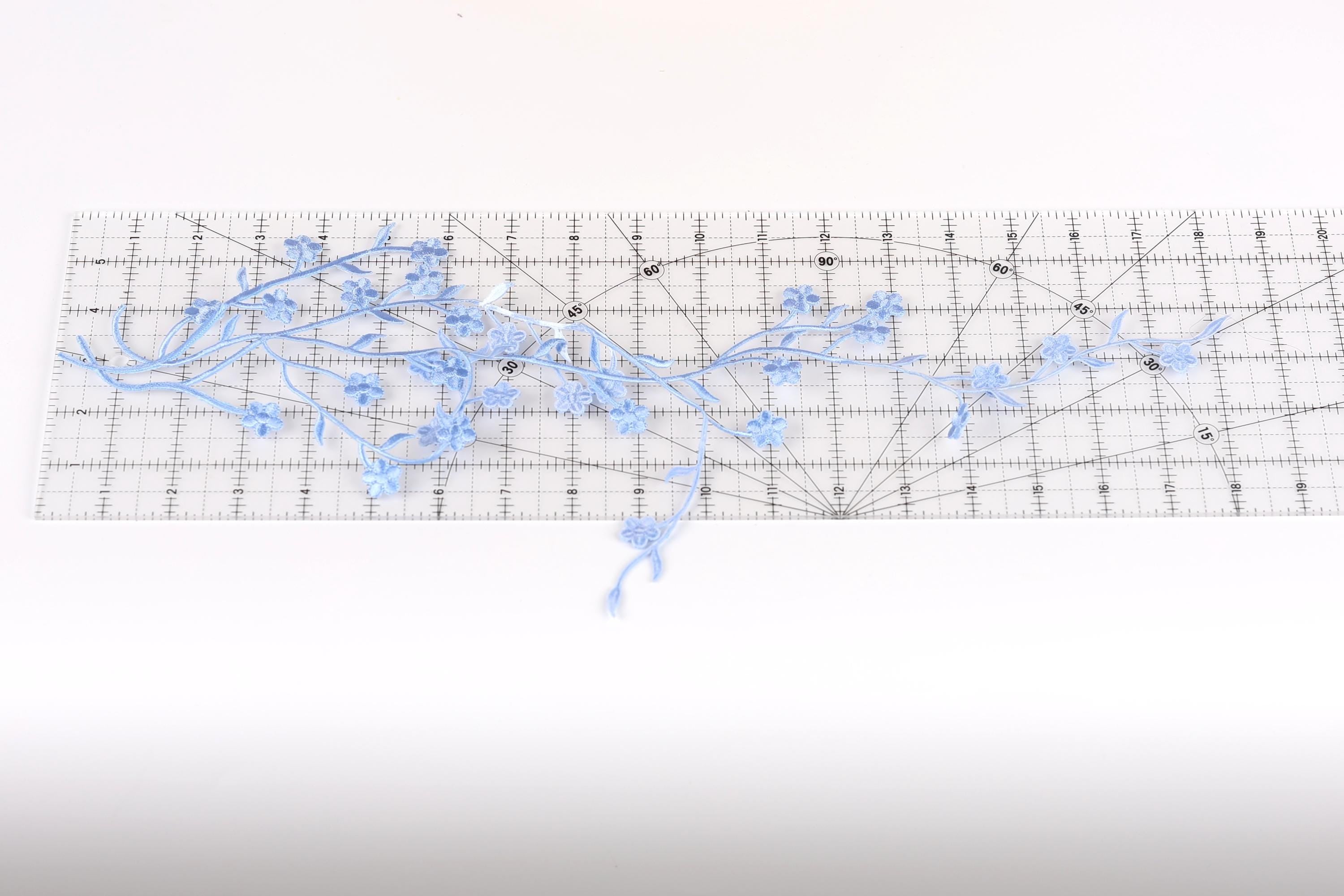 a clear ruler with blue flower-like designs placed on it.