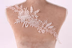 A close-up of a mannequin torso wearing a delicate, intricate lace piece on the shoulder.