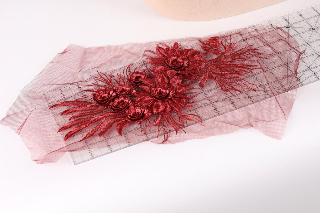 a close-up view of a red floral embroidery on a piece of fabric, with a ruler visible in the background.