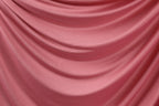 a close-up view of a pink satin fabric, with its folds and creases creating a textured and flowing appearance.