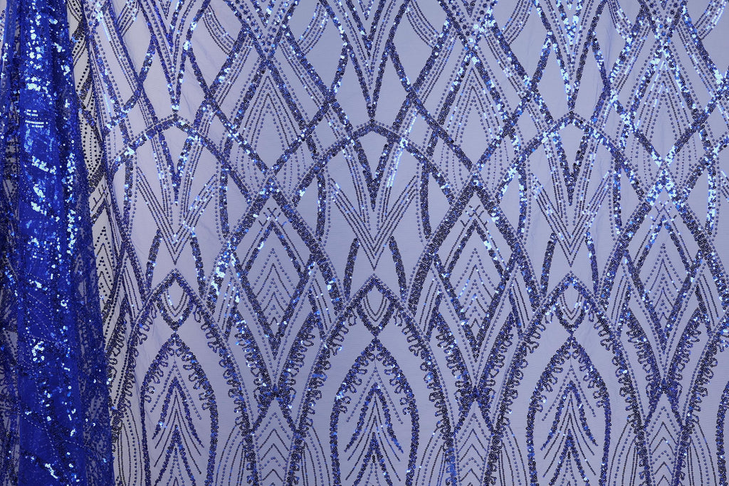 a close-up view of a fabric with a repeating pattern of blue sequin designs. The pattern consists of various diamond shapes and lines, creating a visually striking and intricate design. The fabric appears to be a piece of clothing or textile, with the blue sequins adding a vibrant and eye-catching element to the overall design.