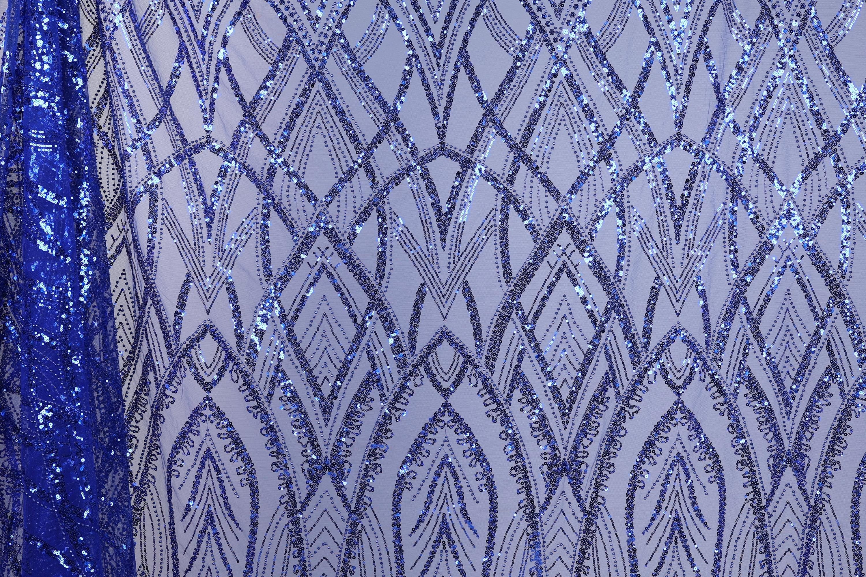 a close-up view of a fabric with a repeating pattern of blue sequin designs. The pattern consists of various diamond shapes and lines, creating a visually striking and intricate design. The fabric appears to be a piece of clothing or textile, with the blue sequins adding a vibrant and eye-catching element to the overall design.