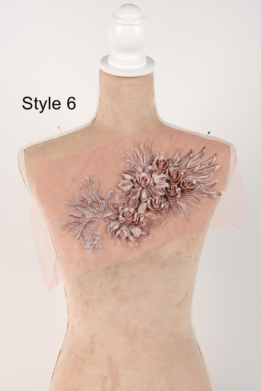 A mannequin wearing a pink floral embroidered patch on its shoulder.