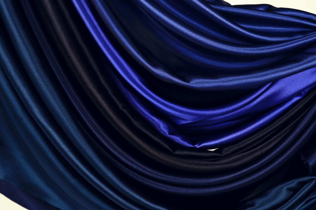 The image is a close-up of a fabric with a gradient of blue and black colors, creating a visually striking and textured appearance.