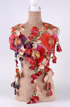 A mannequin wearing a vibrant, colorful necklace made of various flowers and leaves, including red, pink, and purple hues.