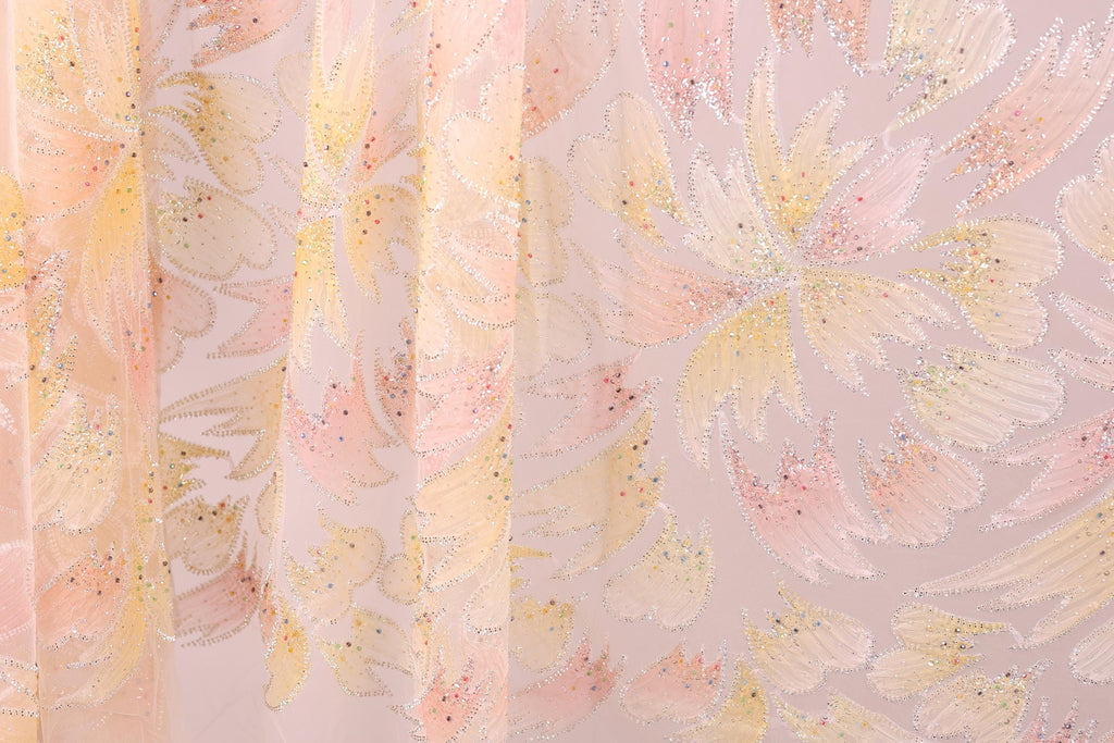 a close-up view of a fabric with a floral pattern in shades of pink and yellow. The fabric appears to be made of sheer material, with a delicate and intricate design.