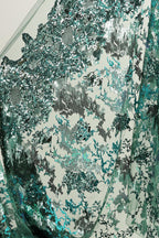 The image is a close-up view of a fabric with a pattern of green and silver sequins or sequin-like material. The fabric appears to be made of a shiny, metallic material, possibly metallic mesh or a similar type of material. The pattern on the fabric is intricate and detailed, with various shades of green and silver sequins or sequin-like elements creating a visually striking and textured appearance.