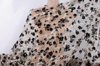 a close-up view of a sheer fabric with a black floral pattern. The fabric appears to be made of sheer material, which is characterized by its transparent and flowing nature. The black flowers on the fabric create a striking contrast against the lighter background, making the fabric visually appealing.