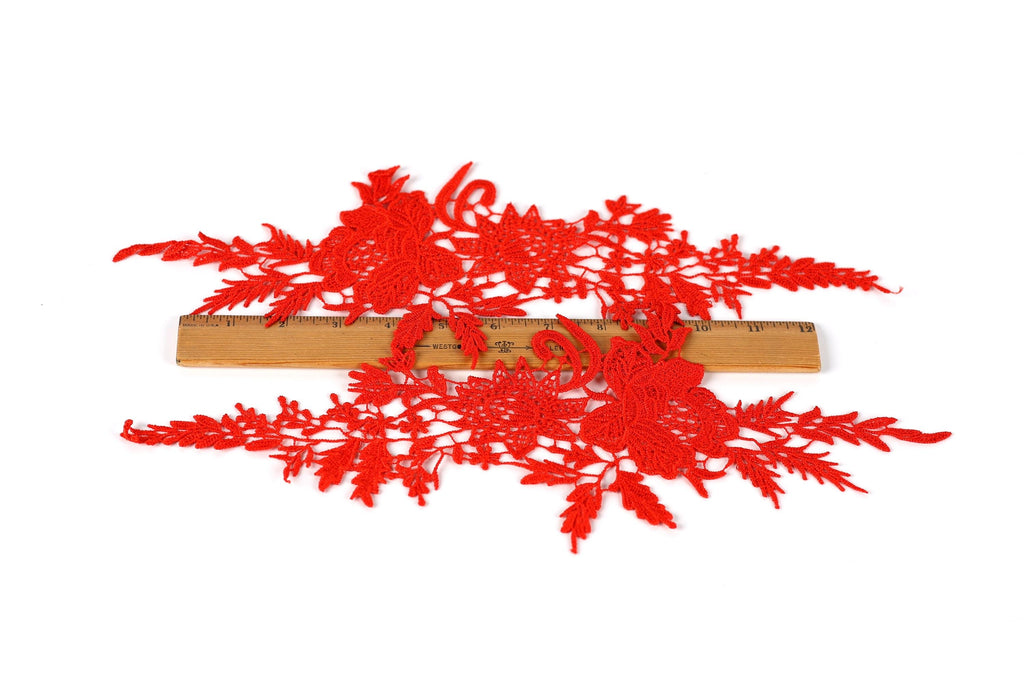 a close-up view of red embroidered or crocheted fabric with intricate floral patterns.