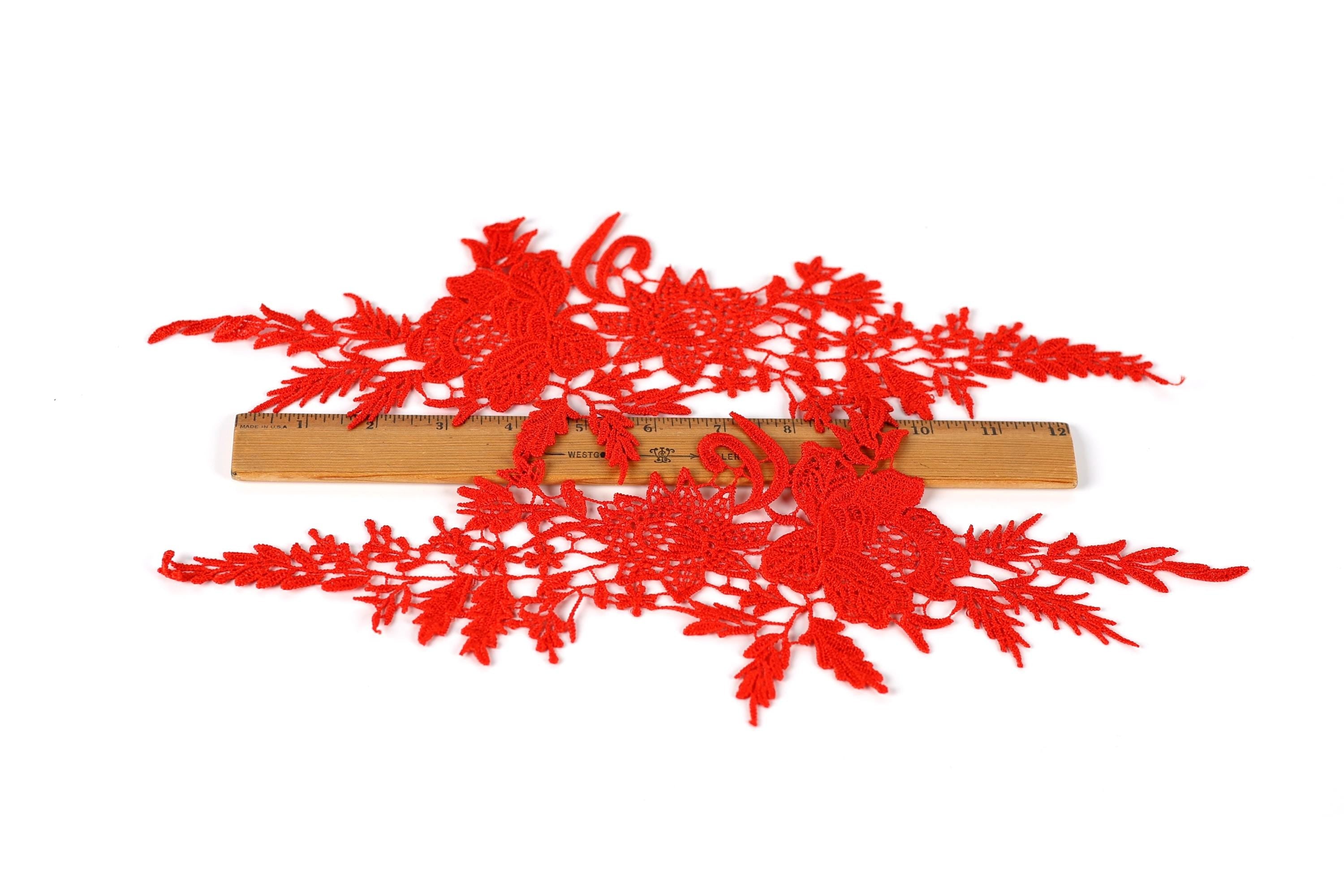 a close-up view of red embroidered or crocheted fabric with intricate floral patterns.