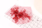 a close-up view of red embroidered flowers on a pink background, with a ruler placed on top of the pink background.