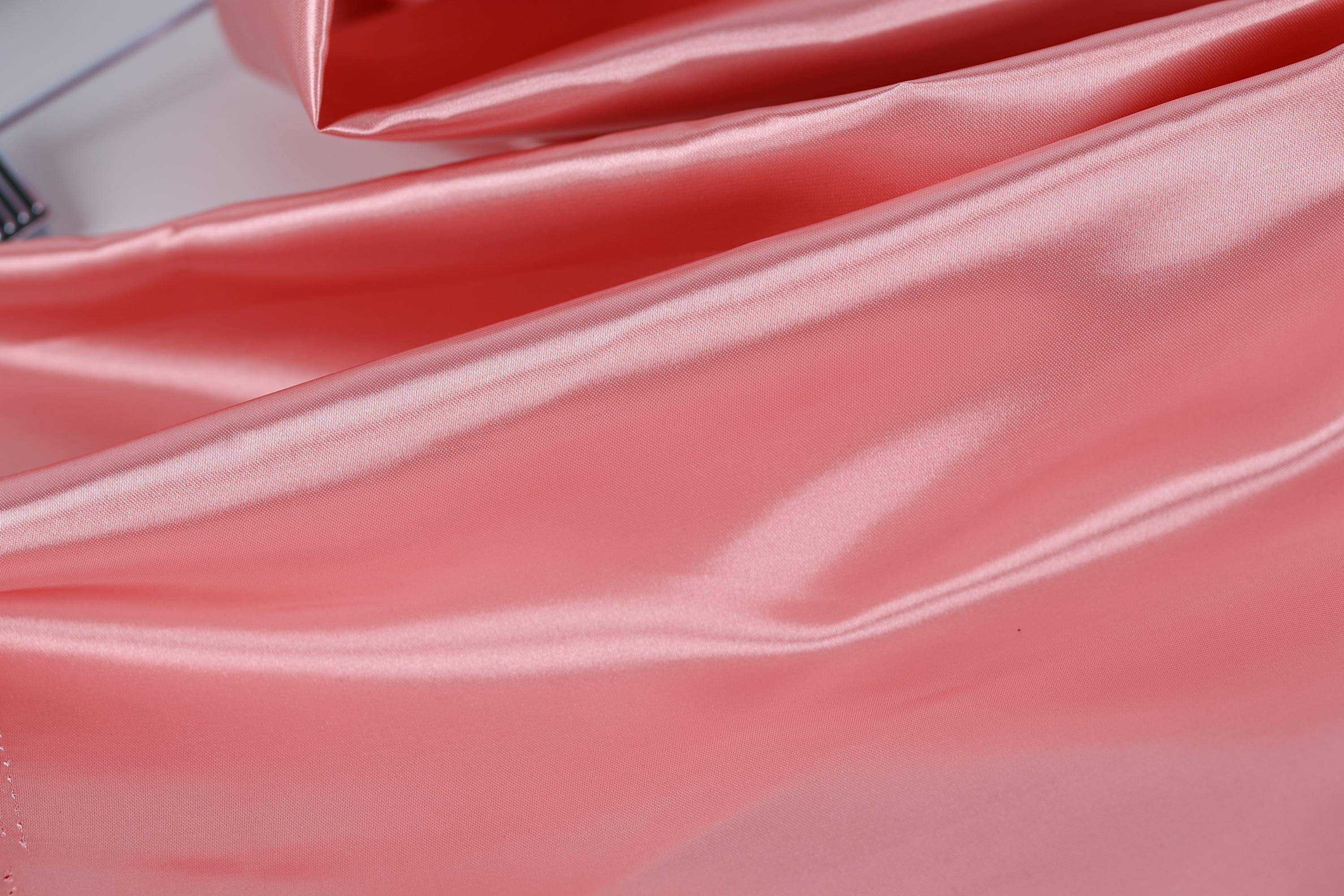 A close-up image of a soft, shiny pink satin fabric, with a smooth and flowing texture.