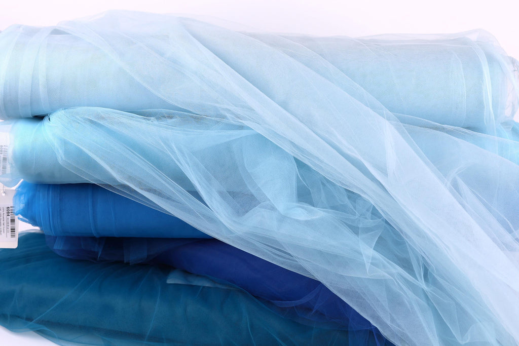 a pile of blue and white tulle fabric, with the blue fabric appearing slightly more vibrant and the white fabric appearing slightly more muted.