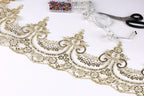 a close-up view of a decorative gold lace trim with intricate floral patterns, along with sewing tools such as scissors and a measuring tape.