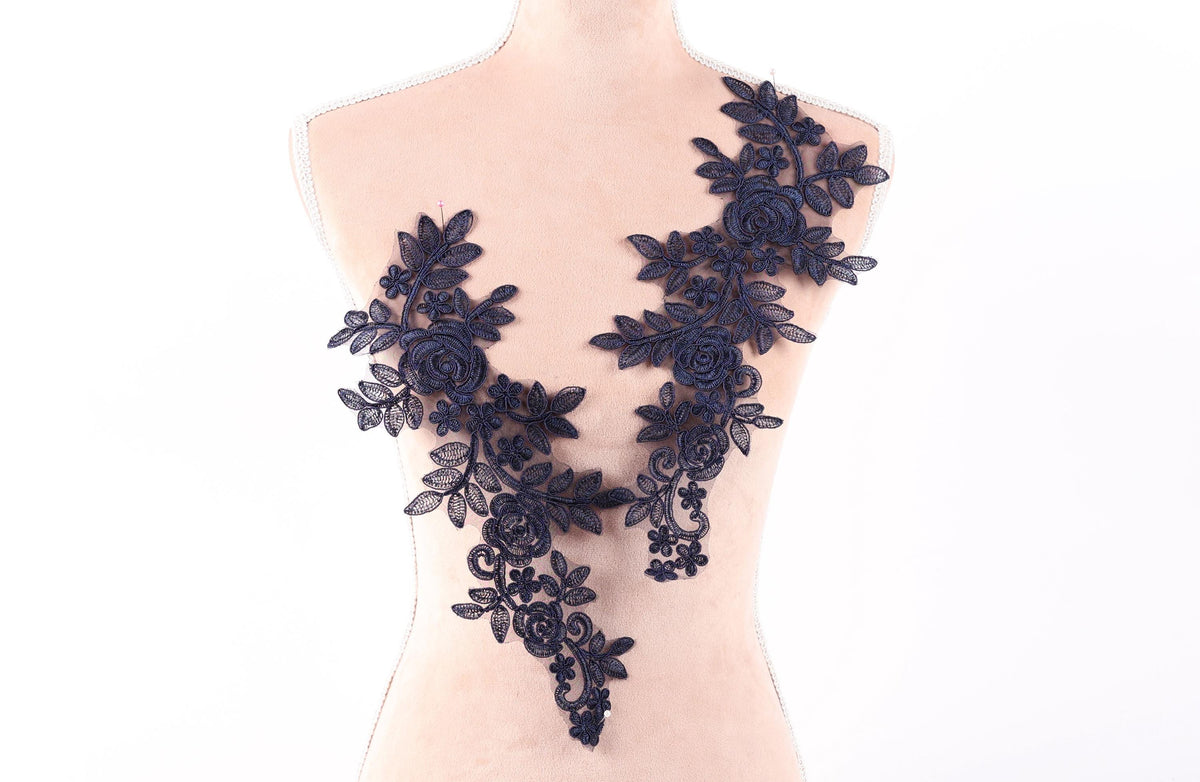 A mannequin torso with a decorative black lace overlay featuring floral and leaf patterns.