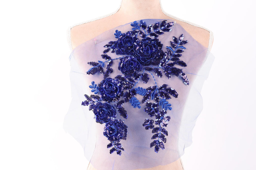 A mannequin wearing a dress with a floral design featuring blue sequins and flowers.