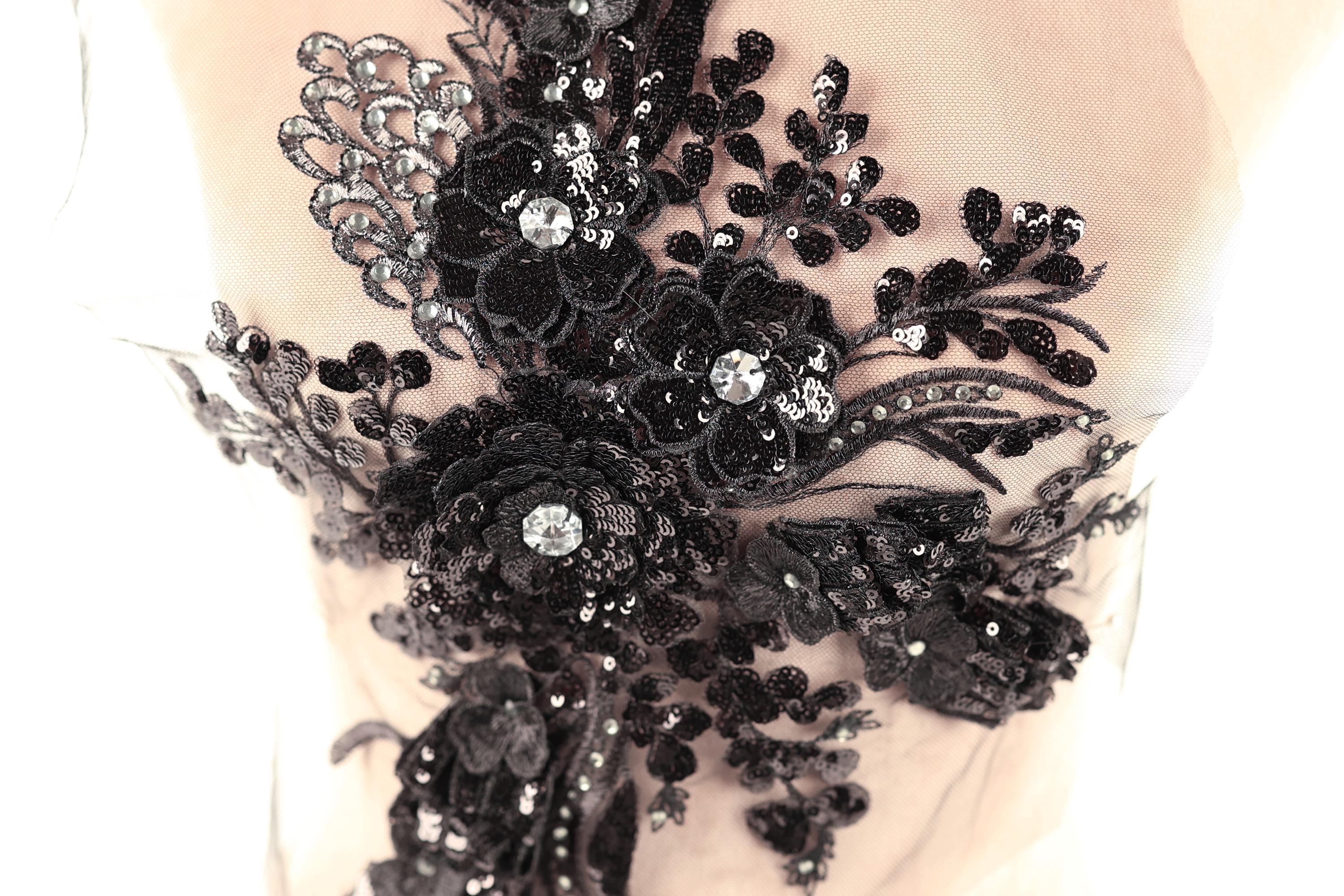 a close-up view of a delicate, intricate black lace piece adorned with sequins and flowers.
