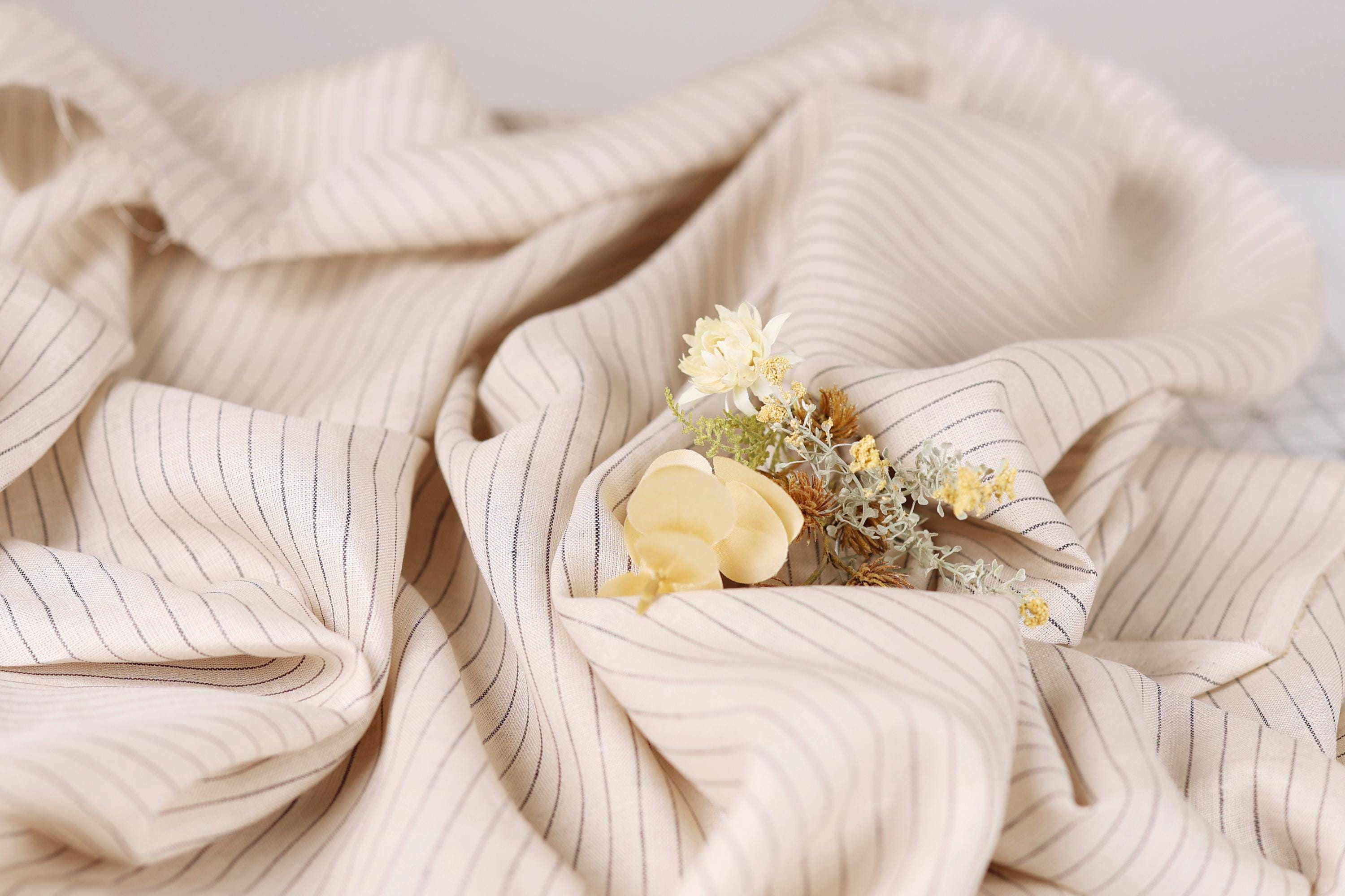 A close-up view of a fabric with white and black striped patterns, featuring a small bouquet of yellow flowers resting on top of it.