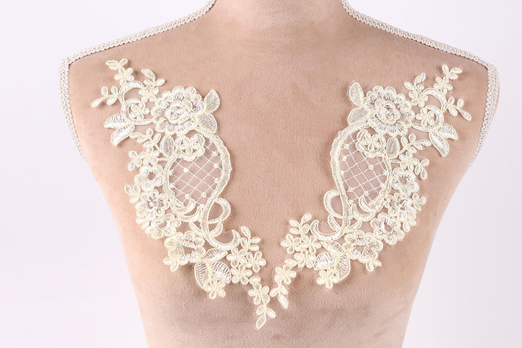 A mannequin torso with delicate white lace fabric sewn onto it, featuring intricate floral and leaf designs.