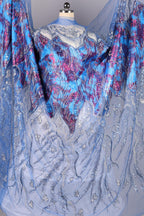 a vibrant and intricate piece of fabric with a striking blue and purple floral pattern. The fabric appears to be made of sheer material, giving it a delicate and airy appearance. The design is detailed and detailed, showcasing the craftsmanship and artistry involved in creating this textile.