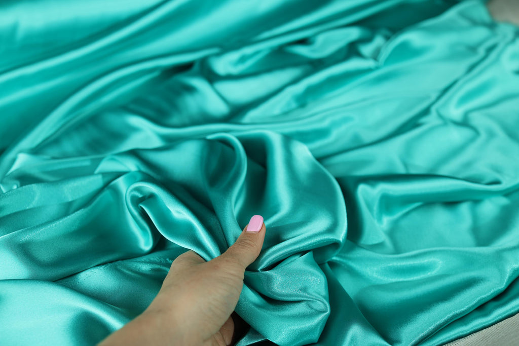 a woman&#39;s hand on a blue satin fabric
