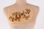 a mannequin torso with a beige fabric piece featuring a floral design and sequin embellishments.