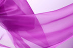 The image is a close-up of a flowing, transparent fabric in a vibrant shade of purple.