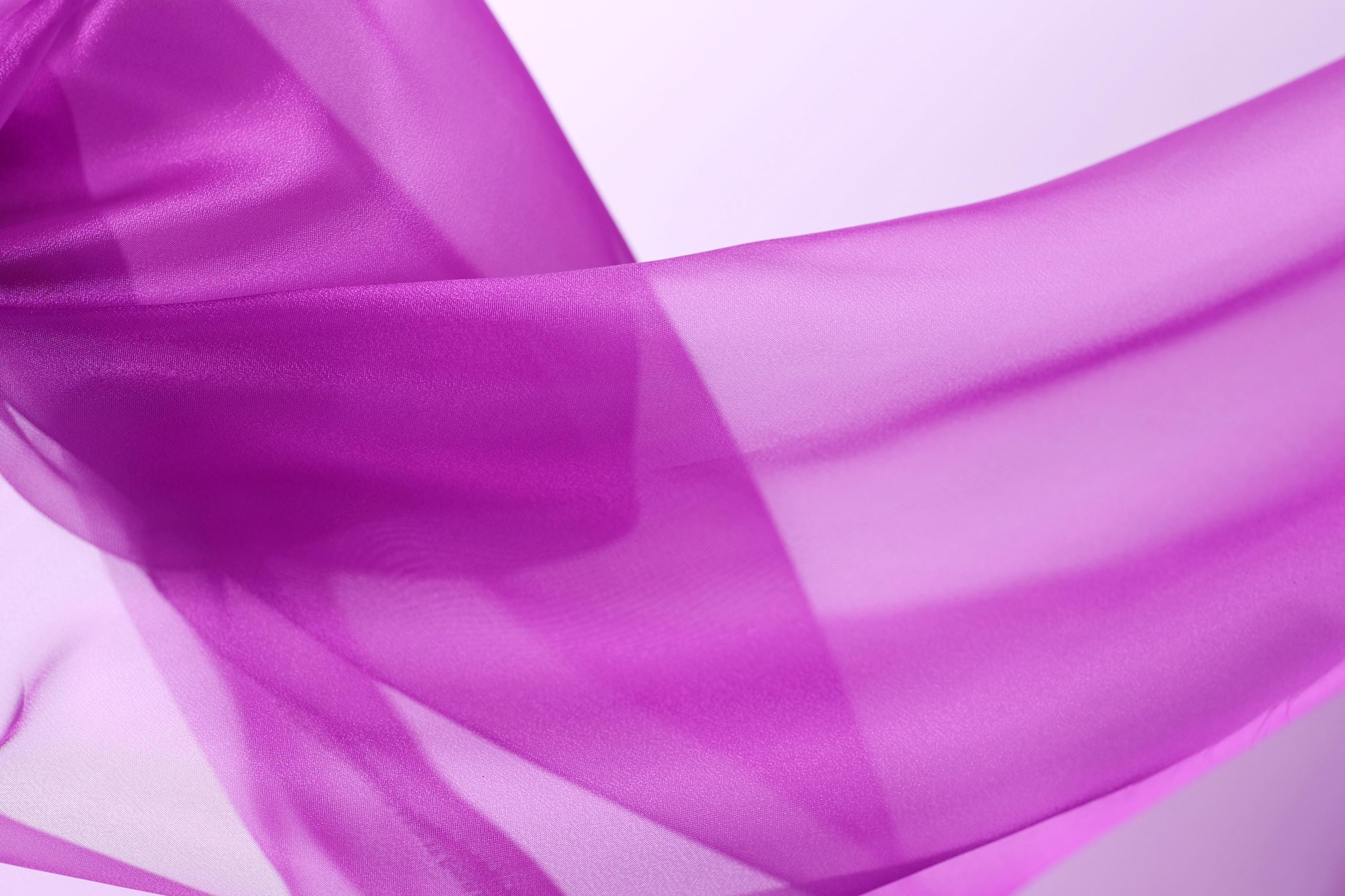 The image is a close-up of a flowing, transparent fabric in a vibrant shade of purple.