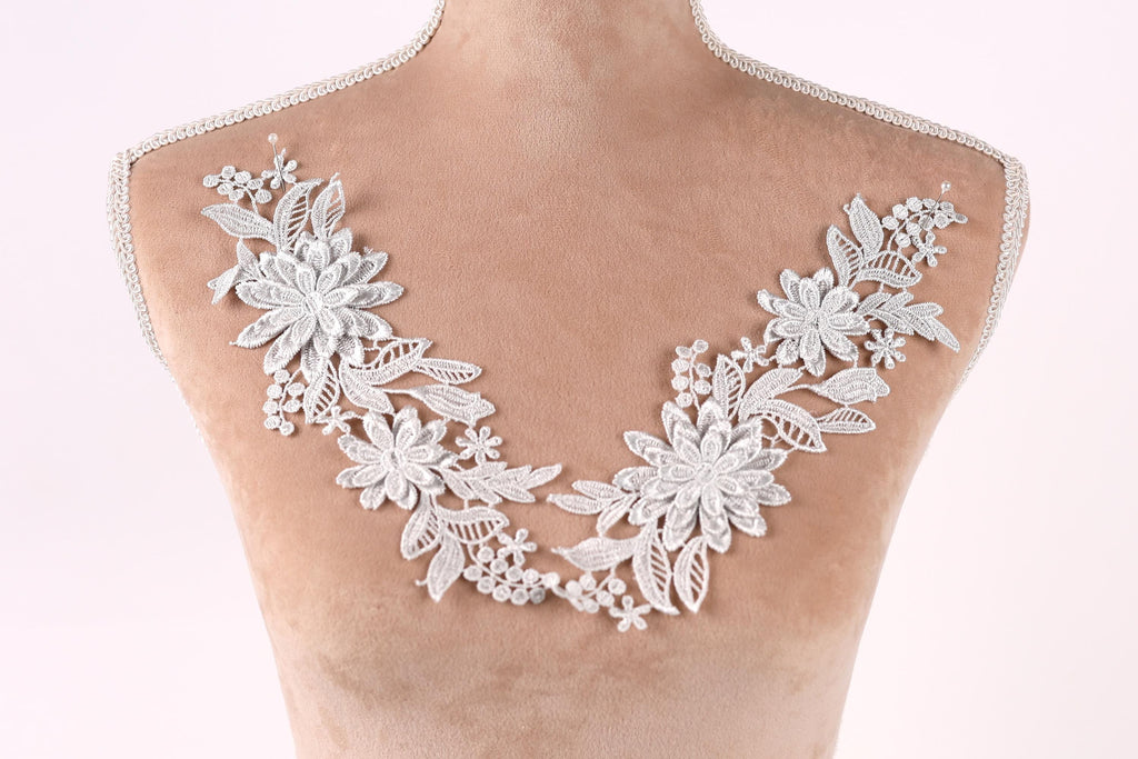 A mannequin torso with a decorative lace overlay featuring white flowers and leaves.
