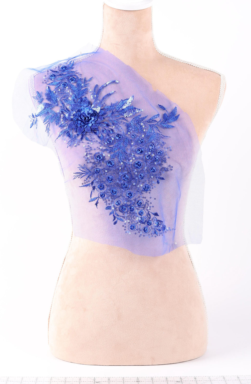 A mannequin torso with a decorative blue floral embroidered on the left side.