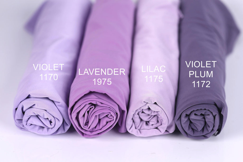 Four rolled-up fabric swatches in different shades of purple, labeled with the names of the colors: violet, lavender, lilac, and plum.