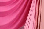 a close-up view of a vibrant pink fabric, with a subtle pink and orange striped pattern. The fabric appears to be soft and flowing, creating a visually appealing contrast against the background.