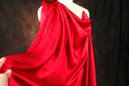 A close-up view of a red satin dress with a draped, flowing silhouette.