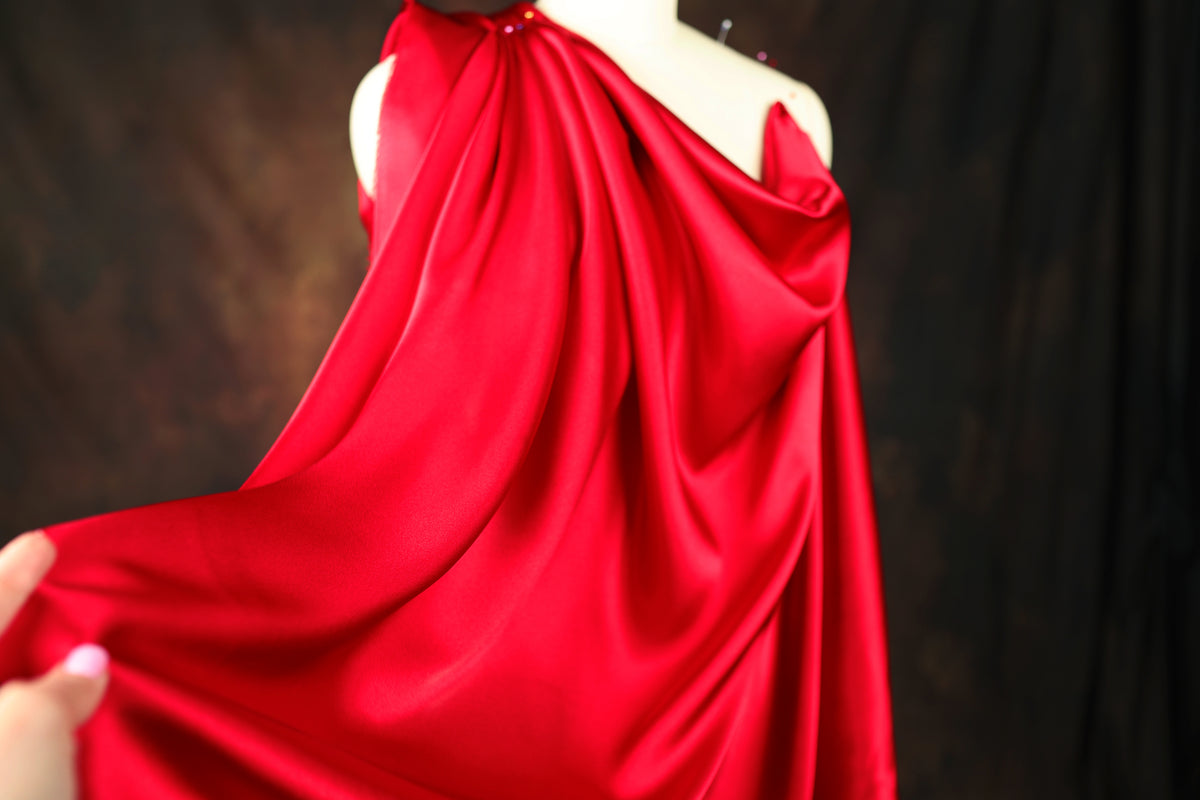 A close-up view of a red satin dress with a draped, flowing silhouette.