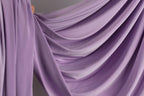 a close-up view of a flowing, purple fabric, possibly a curtain or garment, with a soft, draped appearance.