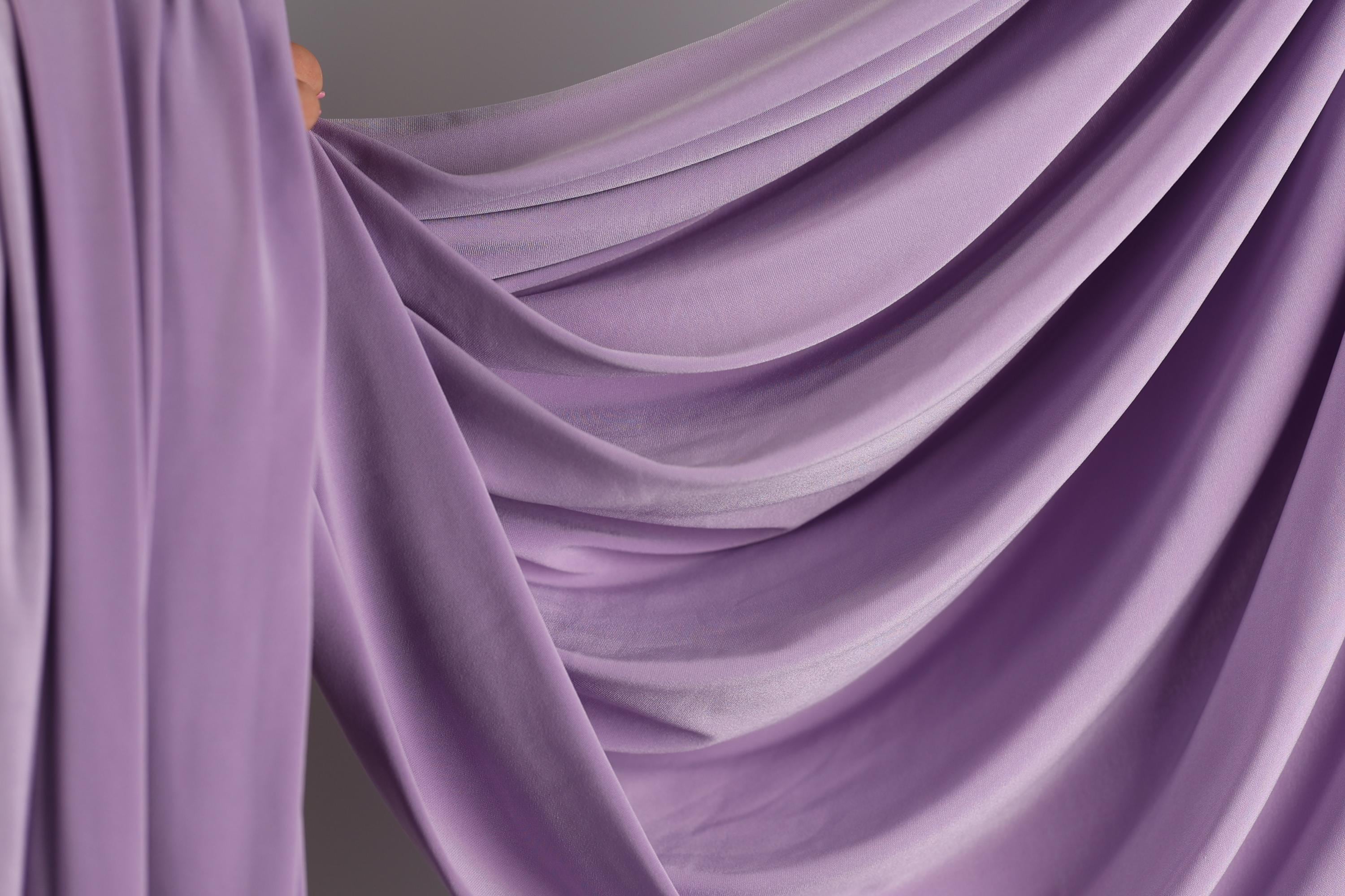 a close-up view of a flowing, purple fabric, possibly a curtain or garment, with a soft, draped appearance.