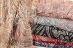 a variety of colorful, sequined fabrics stacked together, showcasing a range of patterns and textures.