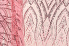 a close-up view of a fabric with a pink and black sequin pattern. The fabric appears to be a sheer material, with a repeating pattern of sequin shapes in shades of pink and black. The pattern is intricate and detailed, with the sequins arranged in a way that creates a visually striking and textured appearance.