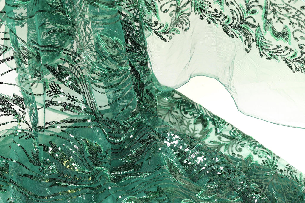 a close-up view of a fabric with a green and black floral pattern, featuring sequins and beads. The fabric appears to be a sheer material, with a delicate and intricate design.