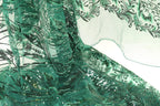 a close-up view of a fabric with a green and black floral pattern, featuring sequins and beads. The fabric appears to be a sheer material, with a delicate and intricate design.