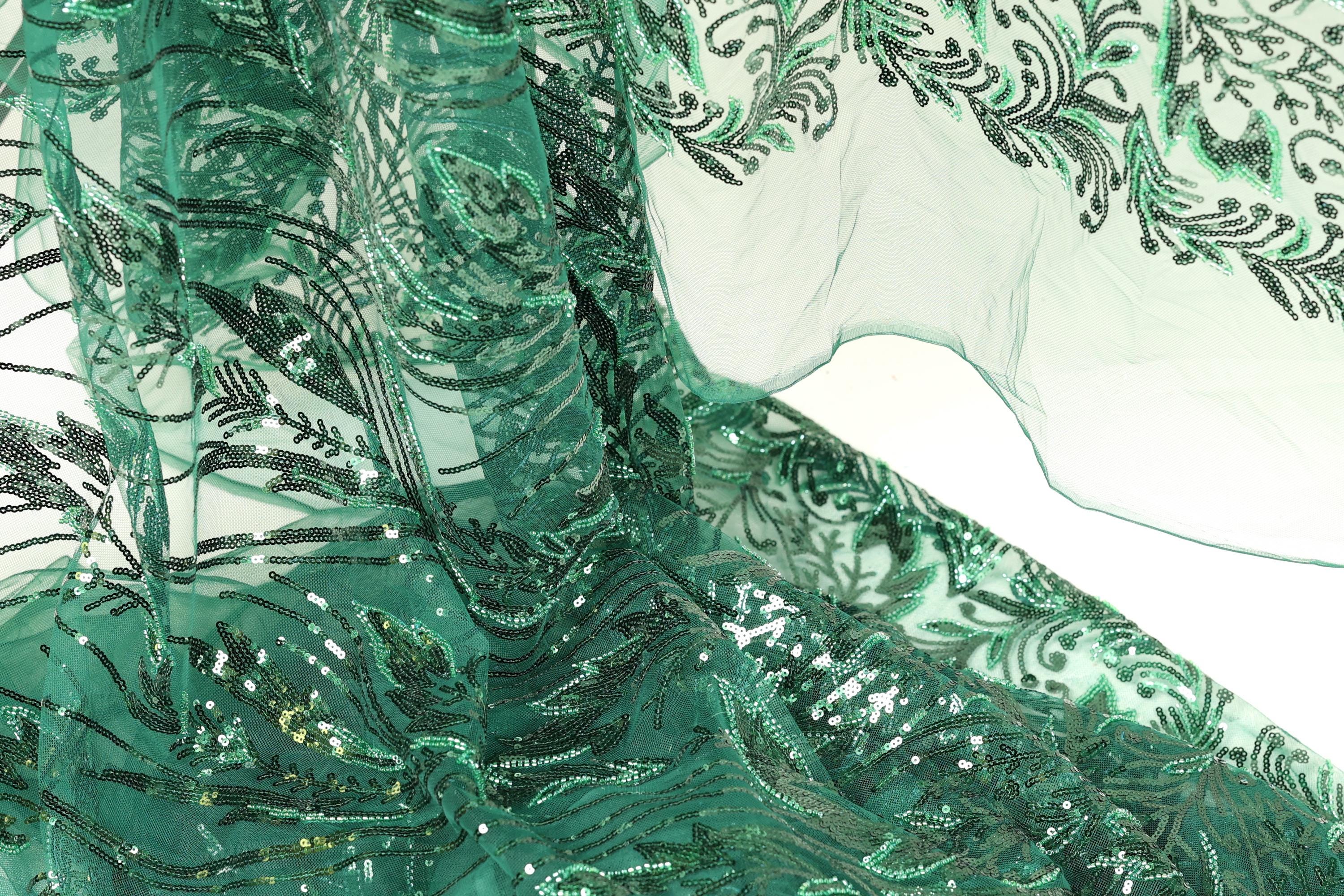 a close-up view of a fabric with a green and black floral pattern, featuring sequins and beads. The fabric appears to be a sheer material, with a delicate and intricate design.