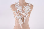 A mannequin wearing a white lace dress with intricate floral patterns.